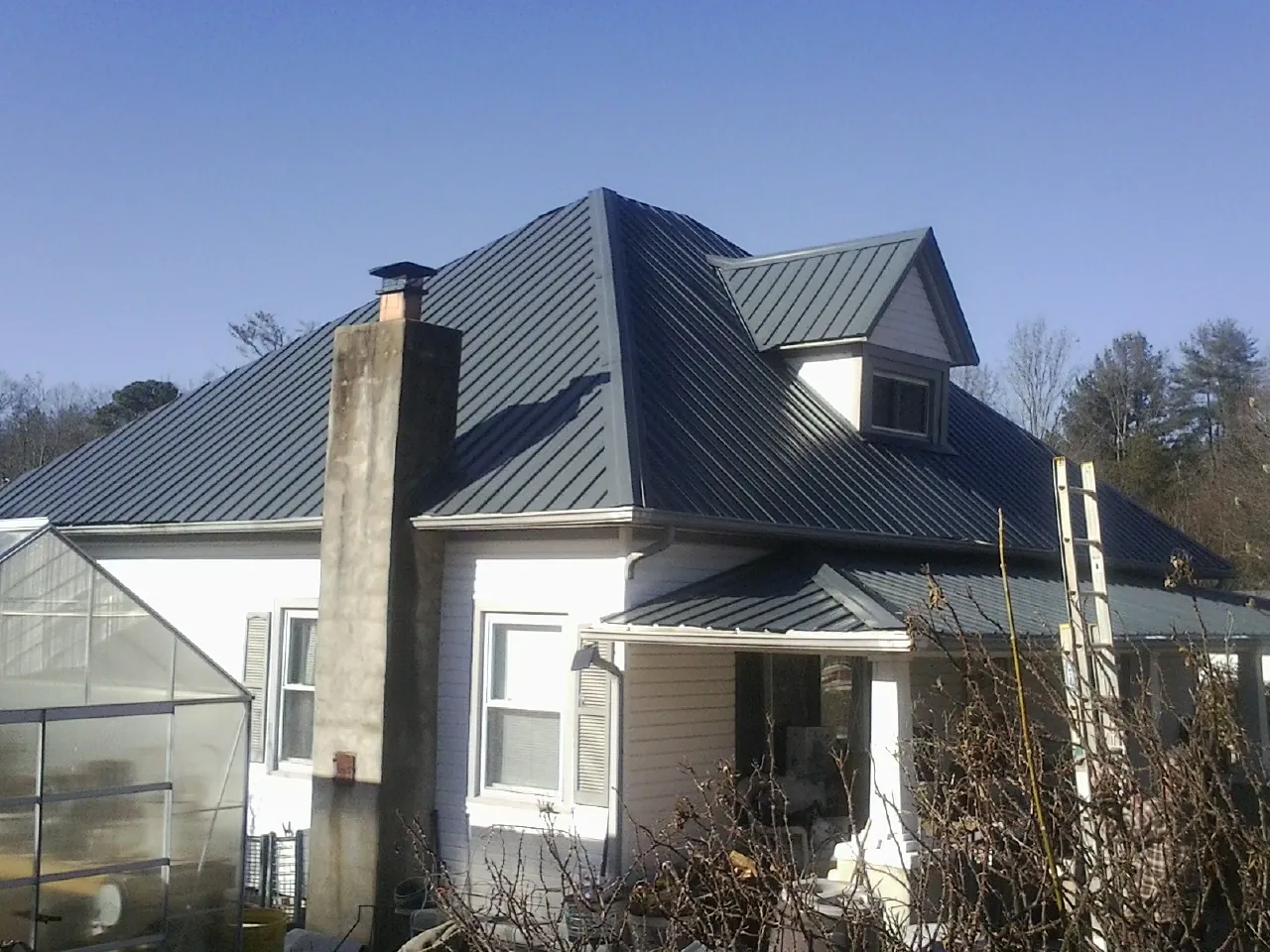 Dark blue standing seam metal roof on a white farmhouse with dormer — Slate & Tile Roof Repair by Roofing Brothers in Joice