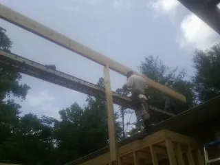 Carpenter setting a ridge beam over a new addition frame — Ice Dam Removal by Roofing Brothers in Joice