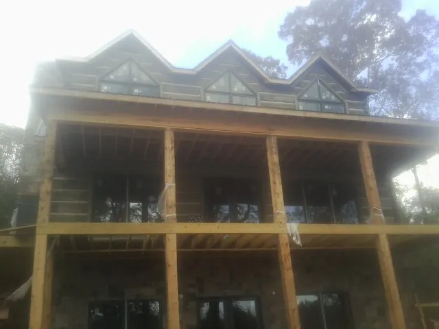 Dormers and porch framing on a large log home under construction — Roof Coating work by our crew in Joice
