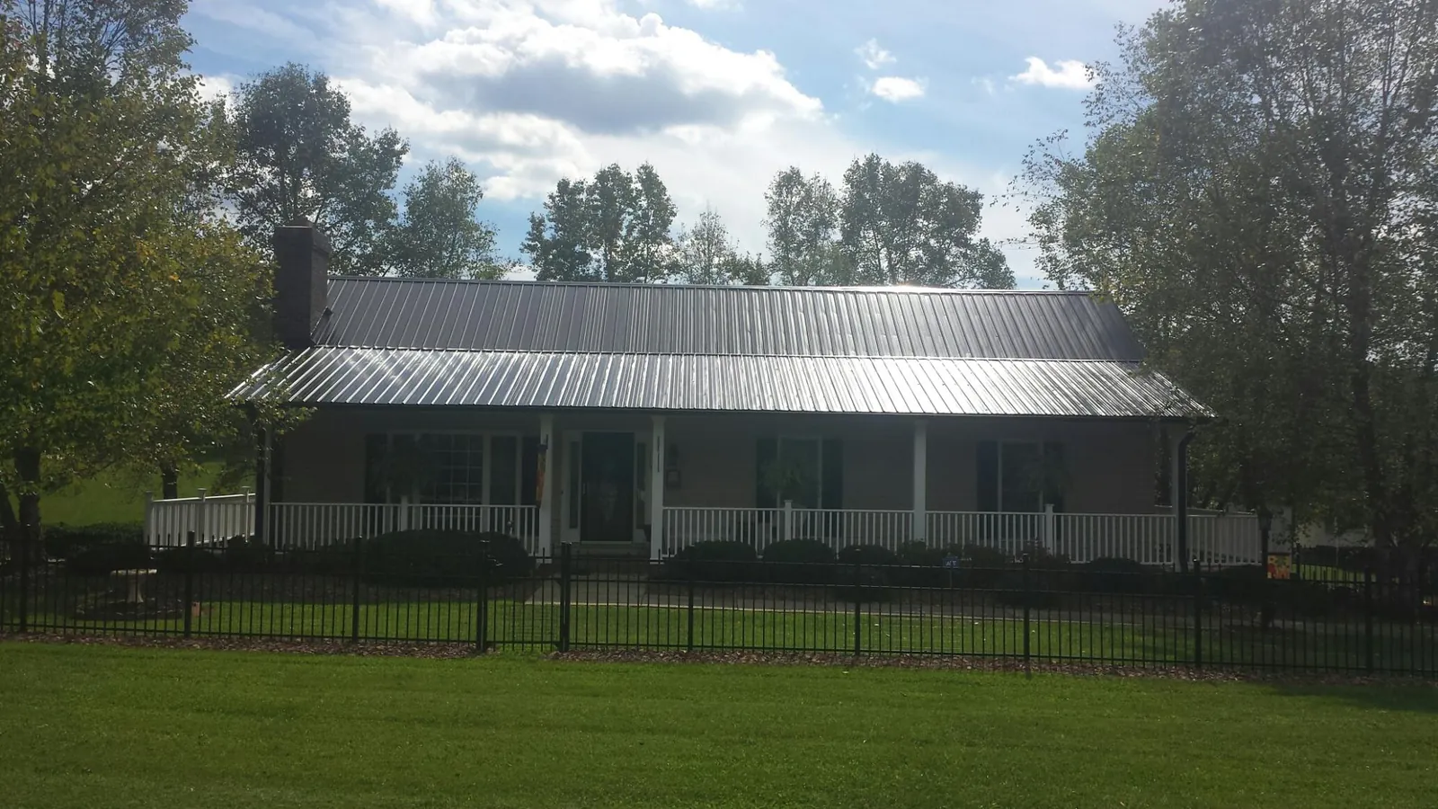Gray metal roof on a brick ranch with a full width front porch — Gutter Guard Installation work by our crew in Joice