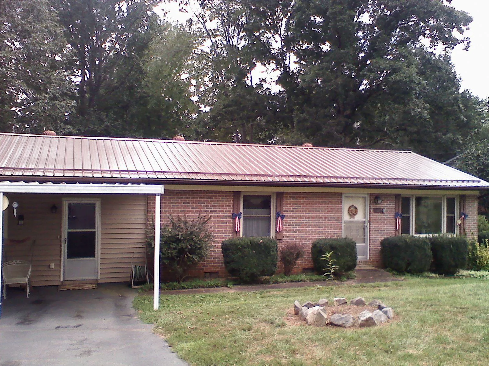 Bronze metal roof and carport on a brick ranch home — Roof Repair work by our crew in Joice
