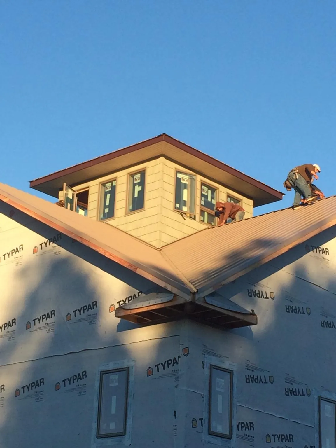 Roofers working around a rooftop cupola on a new metal roof at sunset — Roof Waterproofing in Joice by Roofing Brothers